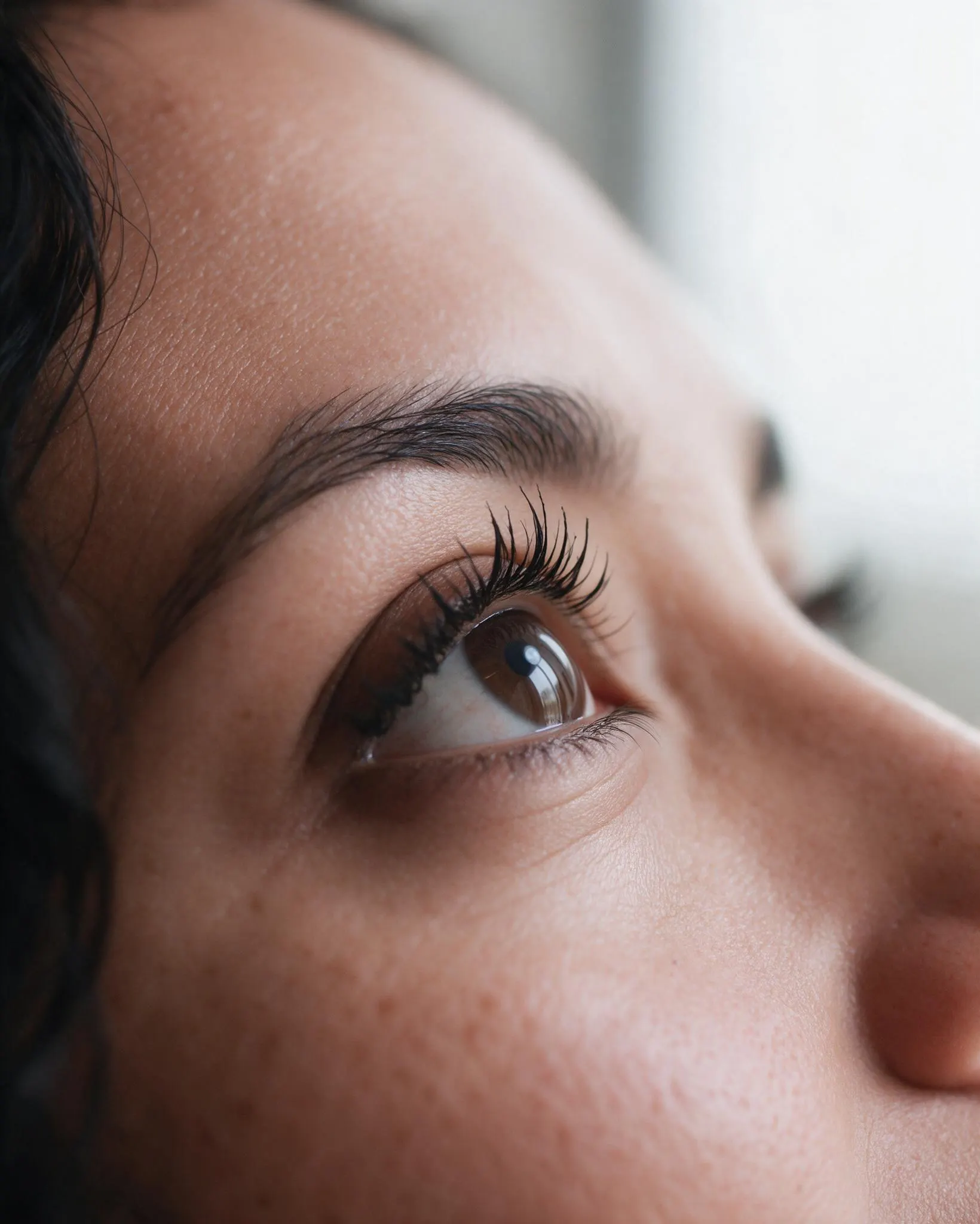 Macro de un ojo abierto mirando hacia arriba, pestañas naturales con rizado y efecto rímel